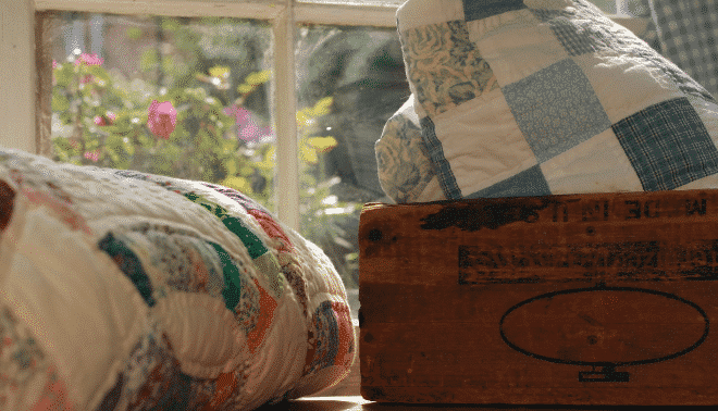 Old folded quilts near a sunny window.