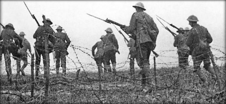 Soldiers in uniform with rifles advance through a barbed wire landscape during wartime.