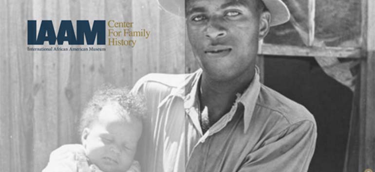 A man holding a baby stands in front of a wooden structure. Text on the image reads, "IAAM Center for Family History, International African American Museum.