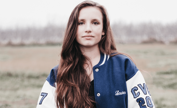 Woman standing outside, wearing a blue and white vintage letterman jacket.