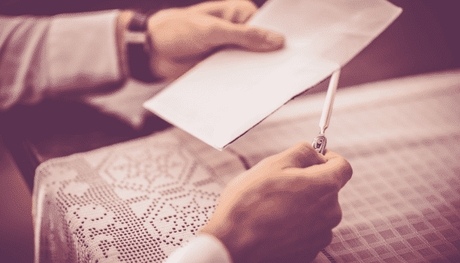 Man wearing grey sweater opening an old greeting card.