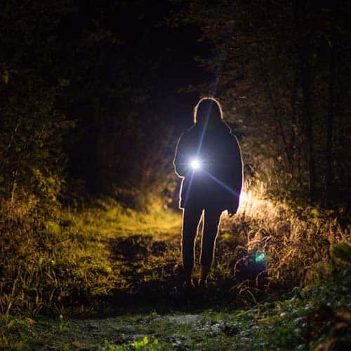 Woman holding a flashlight at night.