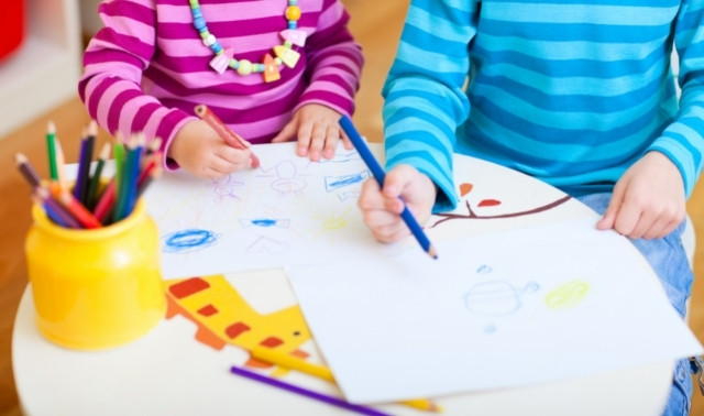 Two children sitting at school table and drawing