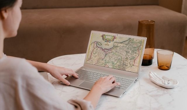 Woman sitting at laptop researching ancestors on map of Prussia