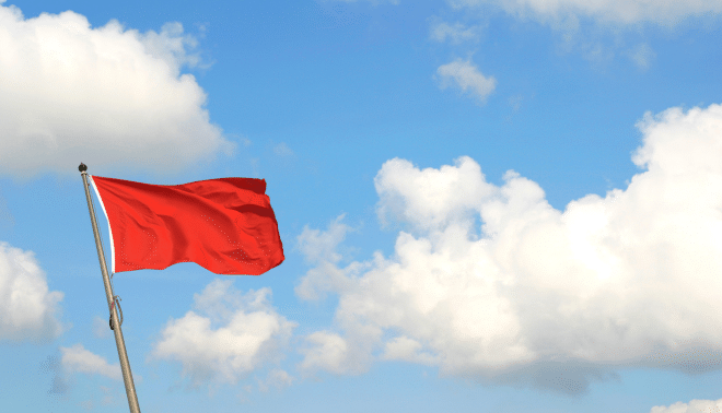 Red flag against a blue sky with clouds.