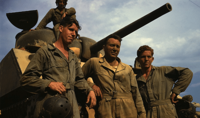 Three soldiers of a US Army tank crew stand in front of a tank