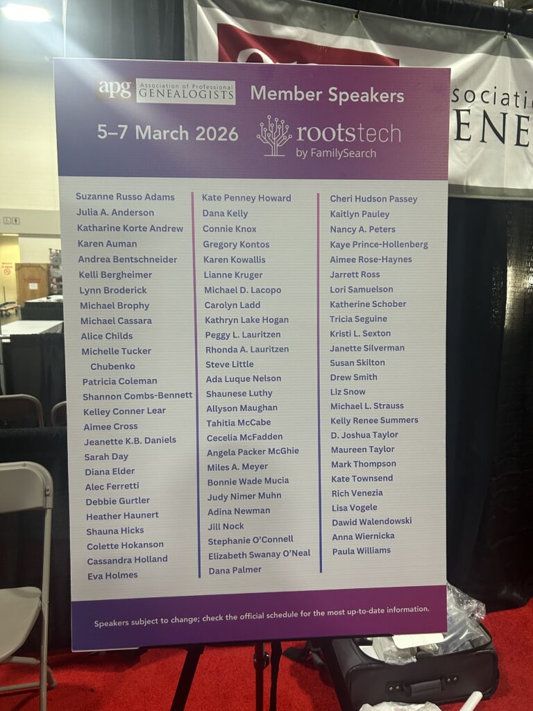 A sign lists the member speakers for the APG event at RootsTech by FamilySearch, scheduled for March 5–7, 2026, with names organized in four columns.
